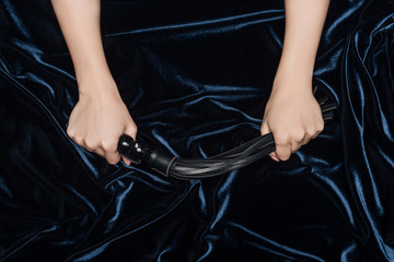close up of female hands tightly holding flogging whip