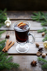 Mulled wine in traditional glass with spices, orange and apple. Closeup view, rustic background