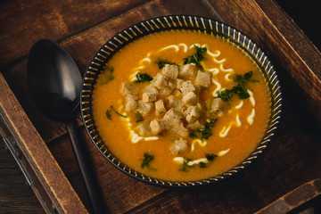 Creamy pumpkin soup with croutons and parsley.