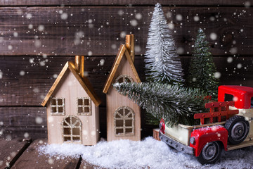 Naklejka premium Decorative tree in red car, houses and fur trees on aged wooden background.