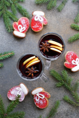 Mulled wine in traditional glass with spices, orange and apple. Top view, gray concrete background