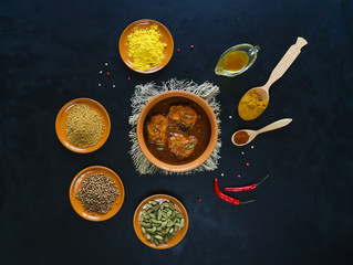 Kerala fish curry and set Indian spices on black table.

