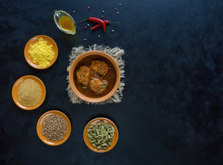 Kerala fish curry and set Indian spices on black table.
