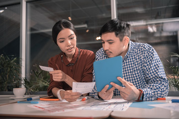 Modern smart freelancers holding blue tablet while working