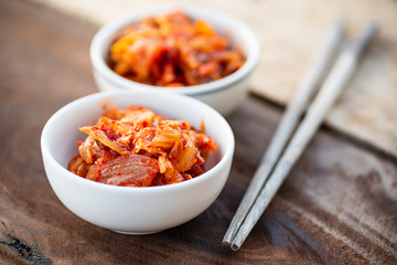Kimchi cabbage in a bowl with chopsticks for eating on wooden table, Korean food