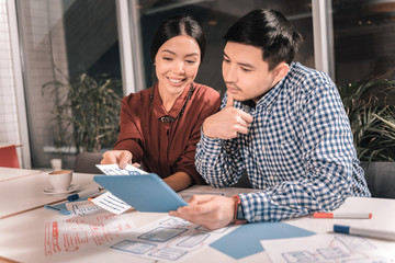 Appealing smiling wife helping her businessman with work