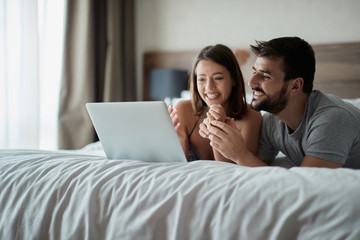 Man and woman at home surfing the net in bed.