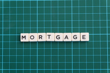 Mortgage word made of square letter word on green square mat background.