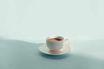 Cup of steaming coffee on seafoam green background. Abstract photo of hot espresso drink on pale blue-green table