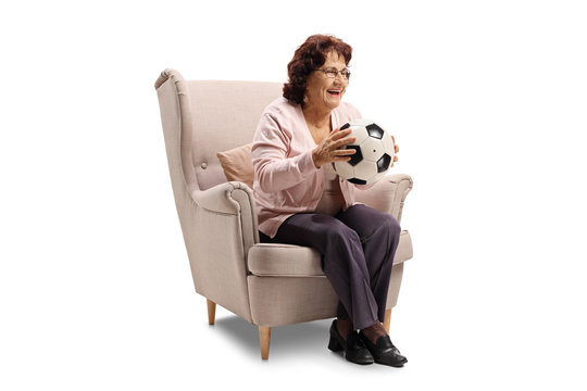 Cheerful elderly woman sitting in an armchair with soccer ball