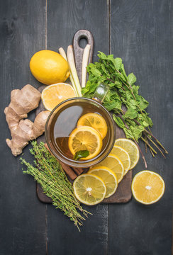 flavored tea with lemon, and herbs, lined with ingredients, mint, thyme, cinnamon and ginger on a wooden rustic background