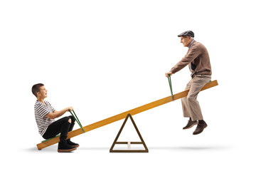 Young boy and an elderly man riding on a seesaw