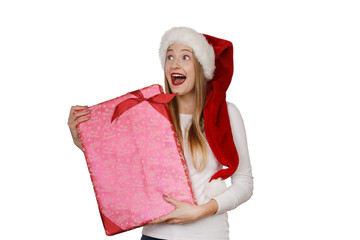 Junge Frau mit Weihnachtsmütze schaut begeistert und hält ein Geschenk in den Armen