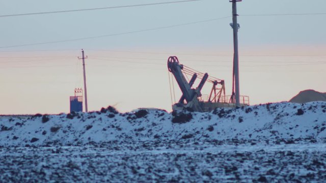 the work of a mining excavator on the background of the winter sunset 4K