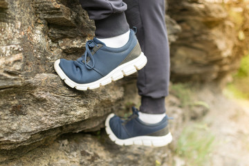 Man in blue sneakers on asphalt at sunset. Men's shoes