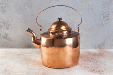 Vintage copper kettle on concrete background.