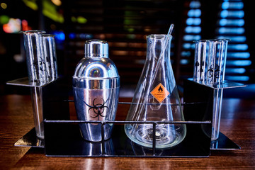 Shaker, flask and test tubes with the symbol of biological hazard, flammable liquid and radiation...