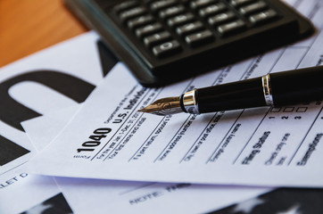 1040 tax form, pen and calculator on the table