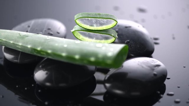 Aloe Vera slices and spa stones rotated closeup. Aloevera plant leaf gel, natural organic renewal cosmetics, alternative medicine. Skin care concept. Slow motion 4K UHD video footage. 3840X2160