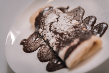 Delicious pancakes topped with chocolate and sugar powder