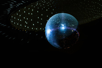 Shiny disco ball on the ceiling. Spinning reflective ball at a festive party. 