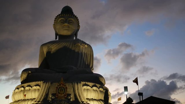 Big buddha statue on hilltop with moving flag in evening time