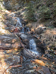 A branch fallen near a mountain stream with ice stalactite formations.