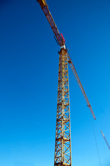 Tower crane against blue sky. Vertical.