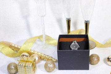 プレゼントの腕時計とシャンパングラスとキラキラな装飾(白背景）