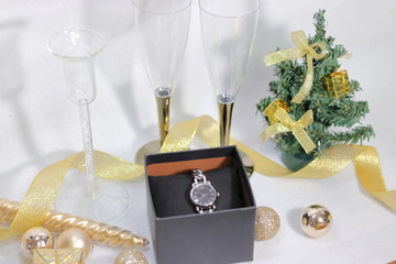 プレゼントの腕時計とシャンパングラスとクリスマスツリーとキラキラな装飾(白背景)	