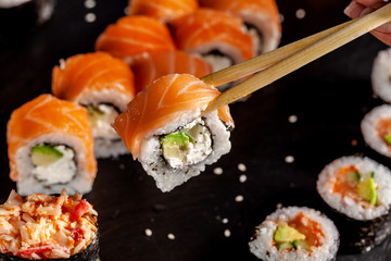 The concept of Japanese and Chinese cuisine. The girl in the restaurant has wooden chopsticks sushi and rolls.