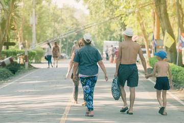 Back view of people walking on the hiking trail in the woods to