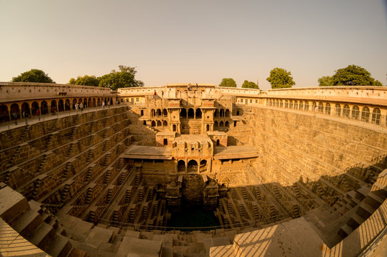 Fisheye shot of the abhaneri stepwell in jaipur rajasthan. Shows the steps, the palace and the green water with all the details of the beautiful stepwell, the surrounding area and the blue sky