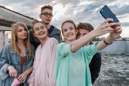 Group of a teenage friends having fun and taking group selfie on the roof of the building 