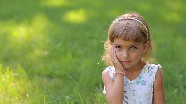 Portrait of a cute little girl in the Park on the grass, her eyes are different colors. Portrait of a small child with heterochromia.
