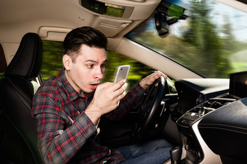 Man sitting inside car with mobile phone in hand texting while driving