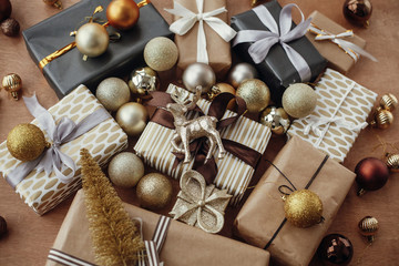 Christmas stylish gift boxes with glitter reindeer,baubles, ornaments on rustic wooden background. Modern black and gold presents. Seasons greetings. Happy holidays. Merry Christmas.