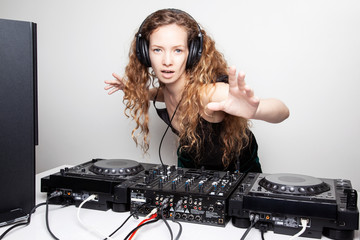 Portrait of curly hair young DJ playing music on light background