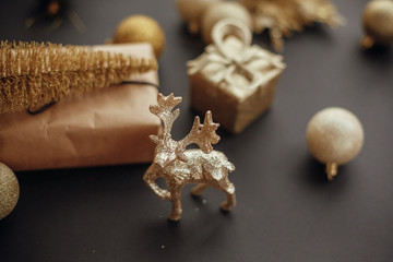 Christmas gold reindeer and gift box with tree on background of glitter baubles on stylish black table. Modern Christmas image . Seasons greetings card. Merry Christmas and Happy New Year
