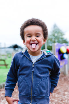 Cheeky little boy outside pulling faces.
