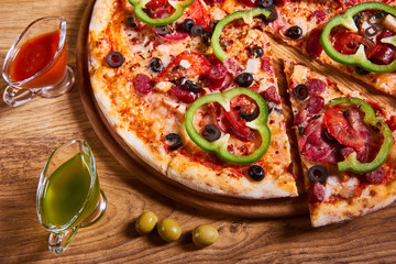 Hot big pepperoni pizza tasty pizza composition with melting cheese bacon tomatoes ham paprika on wooden background