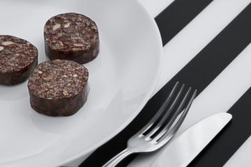 Black pudding on black and white striped background. Morcilla de Burgos
