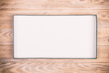 Opened cardboard box on wooden background. vintage, toned top view