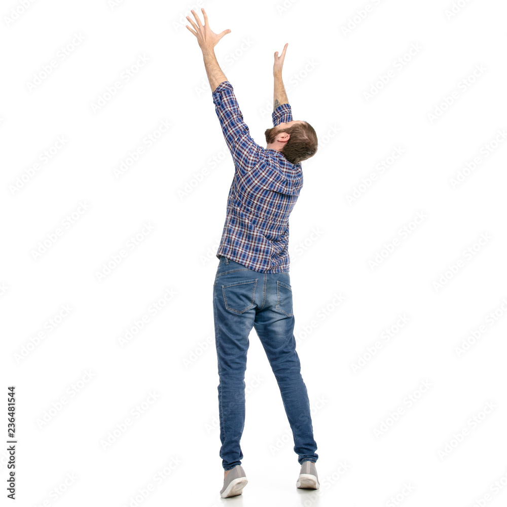 Wall mural A man in jeans hands up holding taking looking up on a white background. Isolation