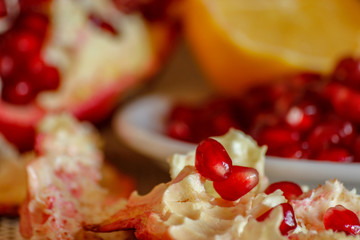 Ripe pomegranate and lemon on a ceramic plate. Close-up, wooden table and rustic background.