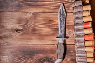 Zelfklevend Fotobehang Old hunting cartridges, a knife and a clip on a wooden table © Vitalii Makarov