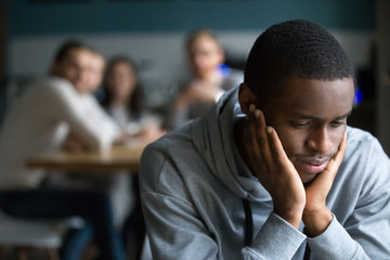 African American millennial guy feel lonely sitting alone in cafe, offended black student avoid...
