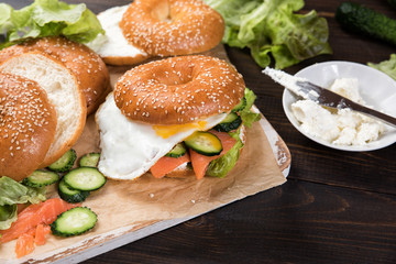 Fresh homemade bagel sandwiches with smoked salmon and low fat cream cheese and an egg. Healthy breakfast food on rustic wooden background