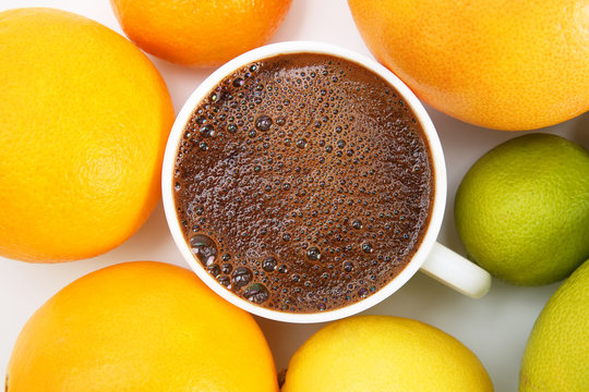 Black coffee in a white Cup surrounded by citrus fruits