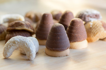 Various kinds of Christmas cookies, cocoa wasp nests, sweet vanilla rolls and cinnamon sandbakelse sweets on wooden table